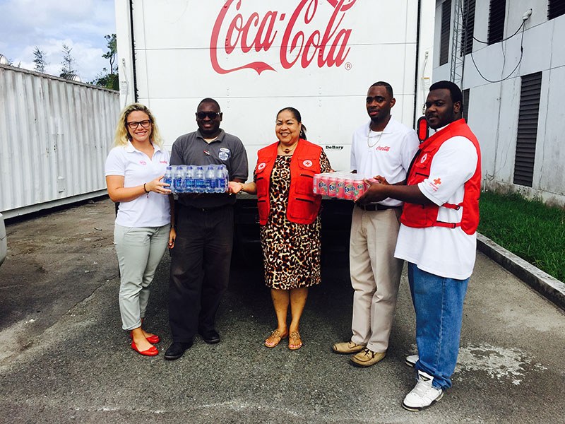 Caribbean Bottling Company staff handing over cases of water to Red Cross volunteers